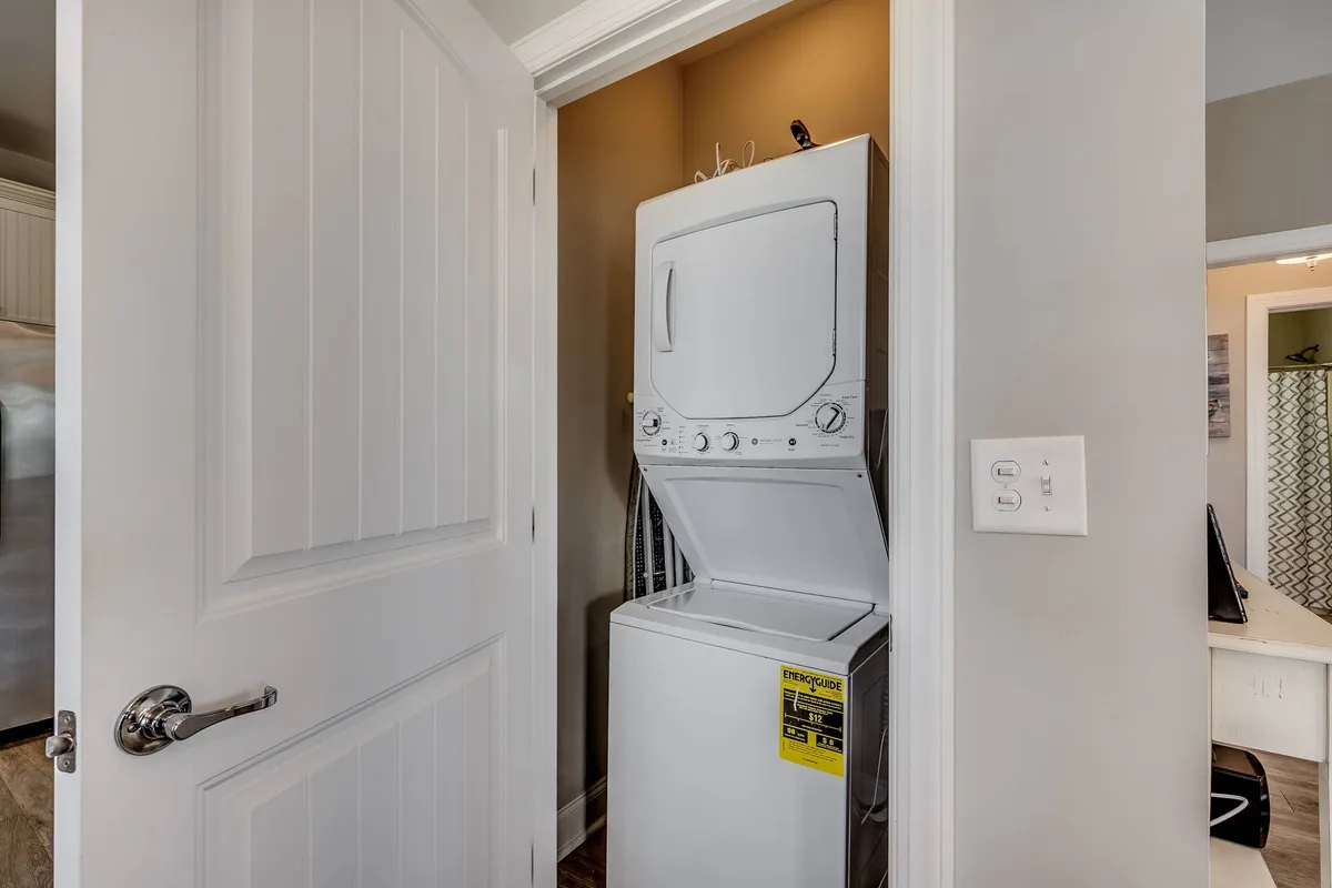 A laundry nook with a stackable washer and dryer neatly tucked behind a doorway, emphasizing convenience and efficiency. The area is simple and practical, tailored for longer stays and effortless daily routines.